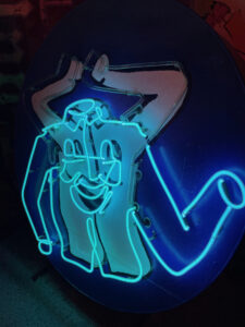 Photo of a vintage neon sign from a dry cleaner, depicting a white button-up shirt with a happy face