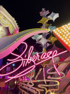 Photo of jumbled vintage neon signs, with pieces of Aladdin's lamp, diamond shapes from the Stardust, and Liberace's signature.