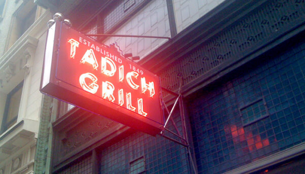 Photo of a vintage neon sign for Tadich Grill, with a slightly foggy background